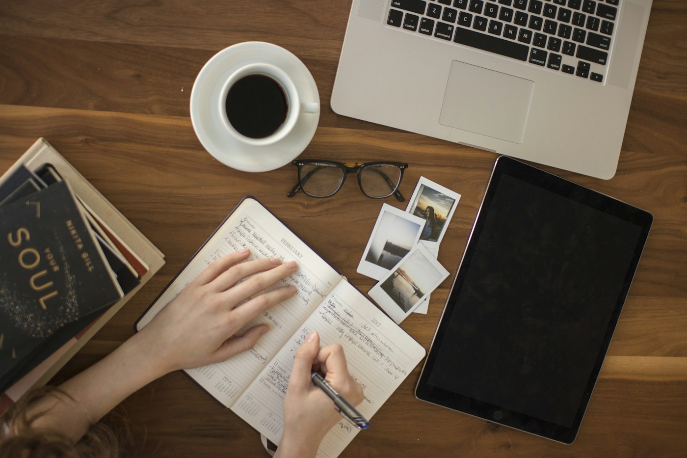 A notebook, coffee, and laptop on a timber desk