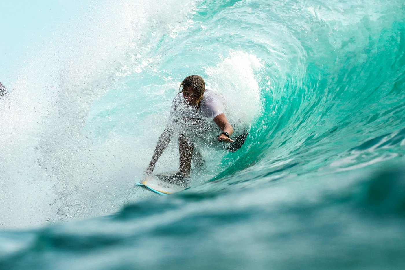 A surfer inside a clear turquoise wave